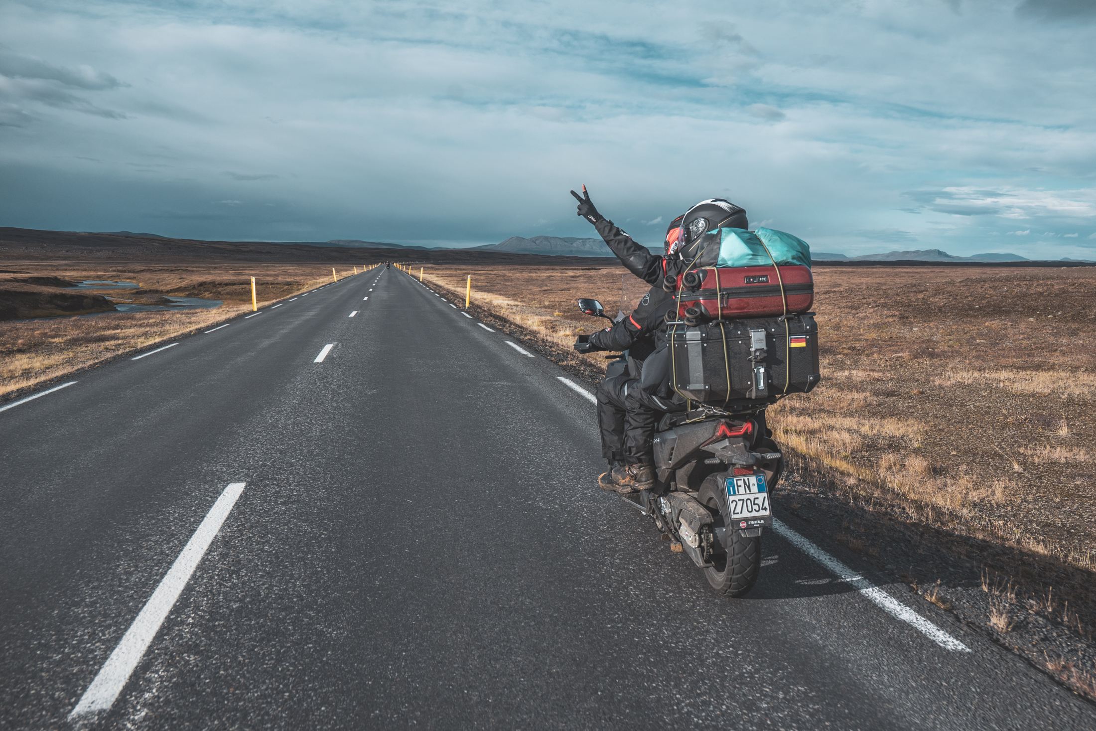 肉比頭騎著滿載行李的機車，行駛在冰島無盡的公路上，比出勝利手勢